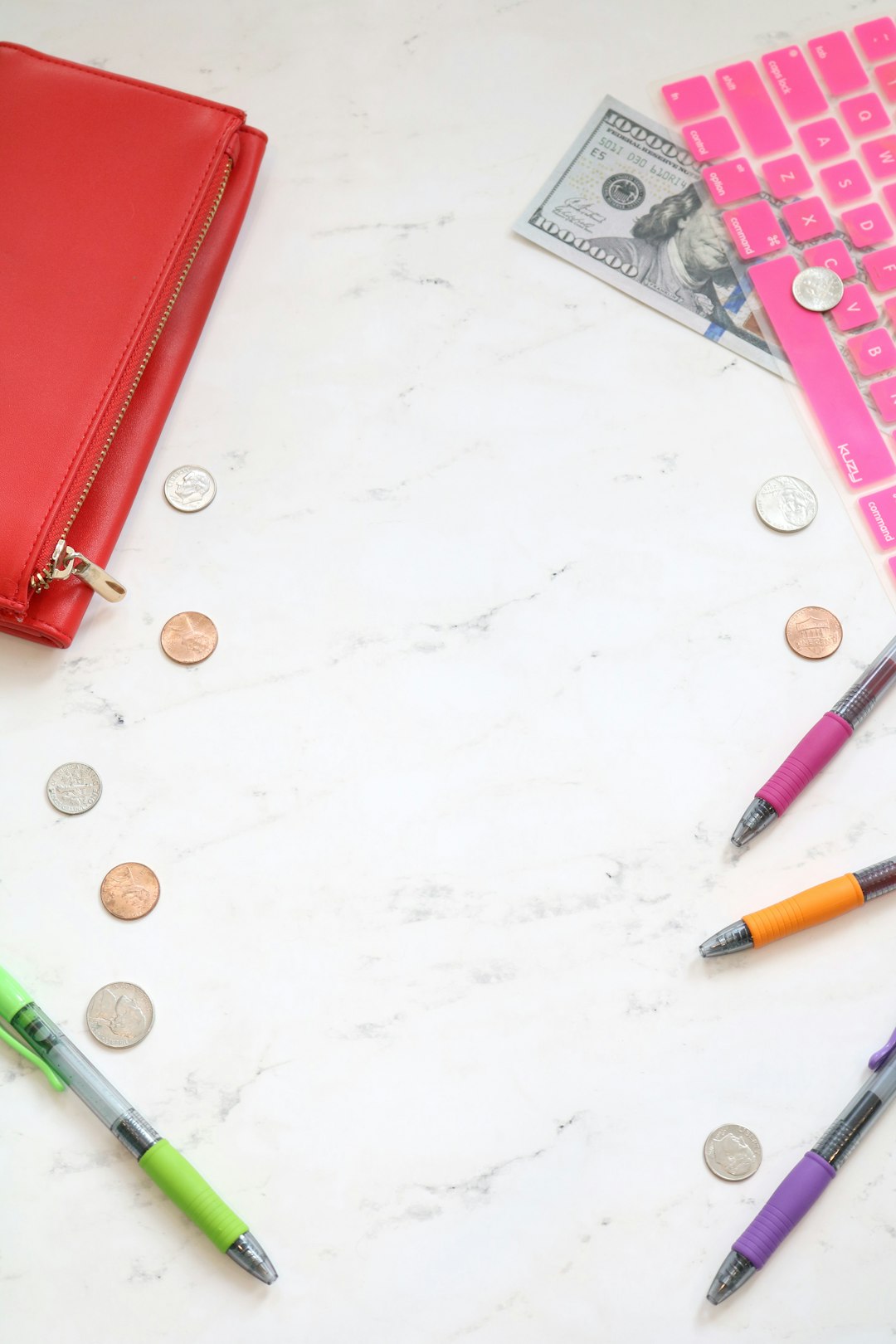 Marble money stock photo and money styled stock photo for personal finance bloggers, business coaches, and entrepreneurs with a pink keyboard, colorful pens, cash, a red wallet, and more.